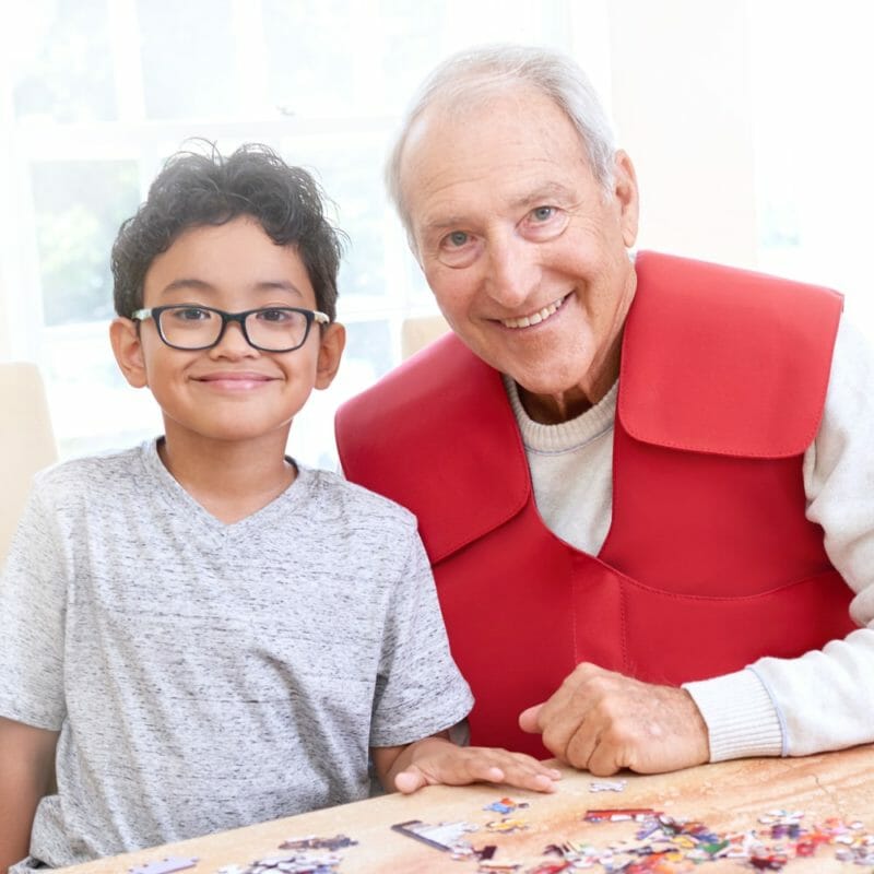 A SmartVest Airway Clearance patient and his grandson assemble a puzzle together while performing therapy.