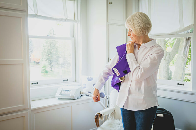 Woman putting on her purple SmartVest at home.