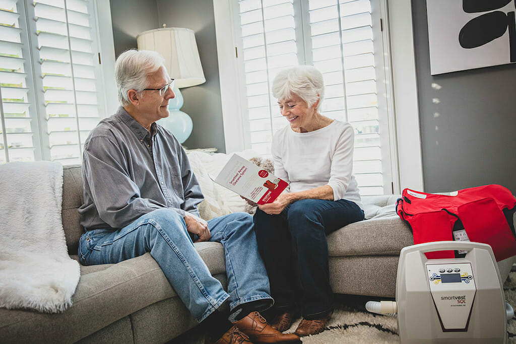 Older man and woman sitting on couch reviewing SmartVest information packet together.