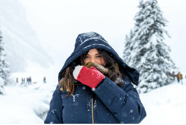 A hiker covers her face while trekking in the snow