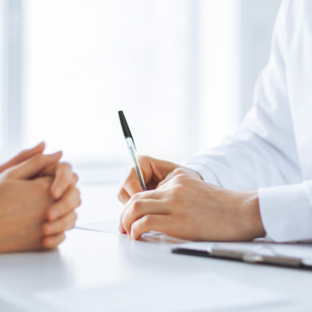 A doctor holds a pen as he meets with his patient