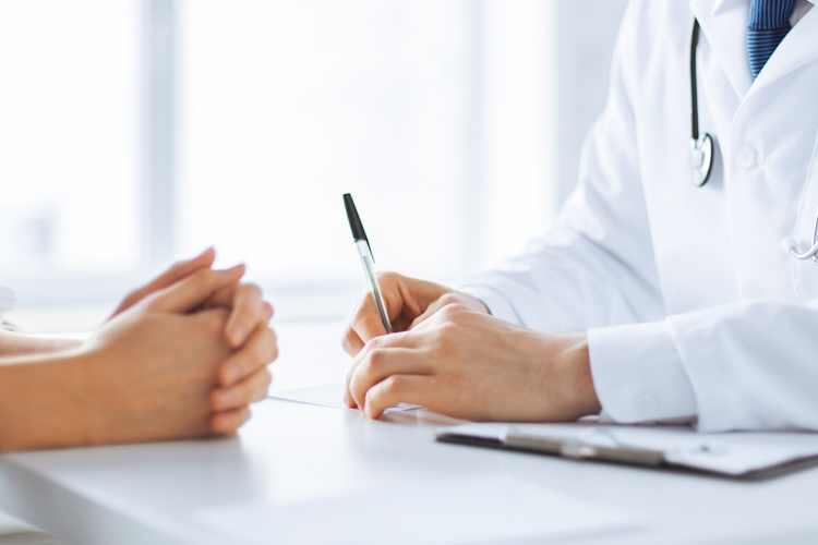 A doctor holds a pen as he meets with his patient