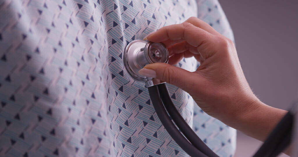 A doctor presses their stethoscope to the chest of a patient