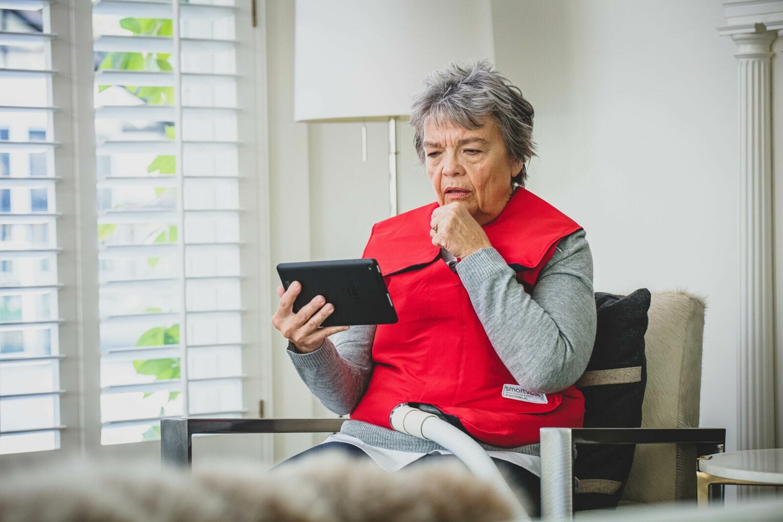 An older woman wearing SmartVest while using a tablet