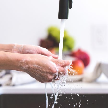 A pair of hands washing eachother under a faucet