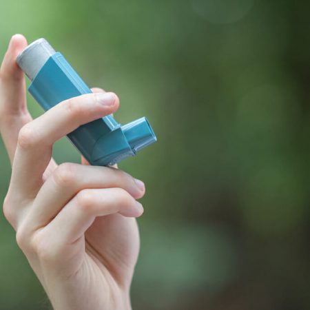 A hand holds an inhaler out