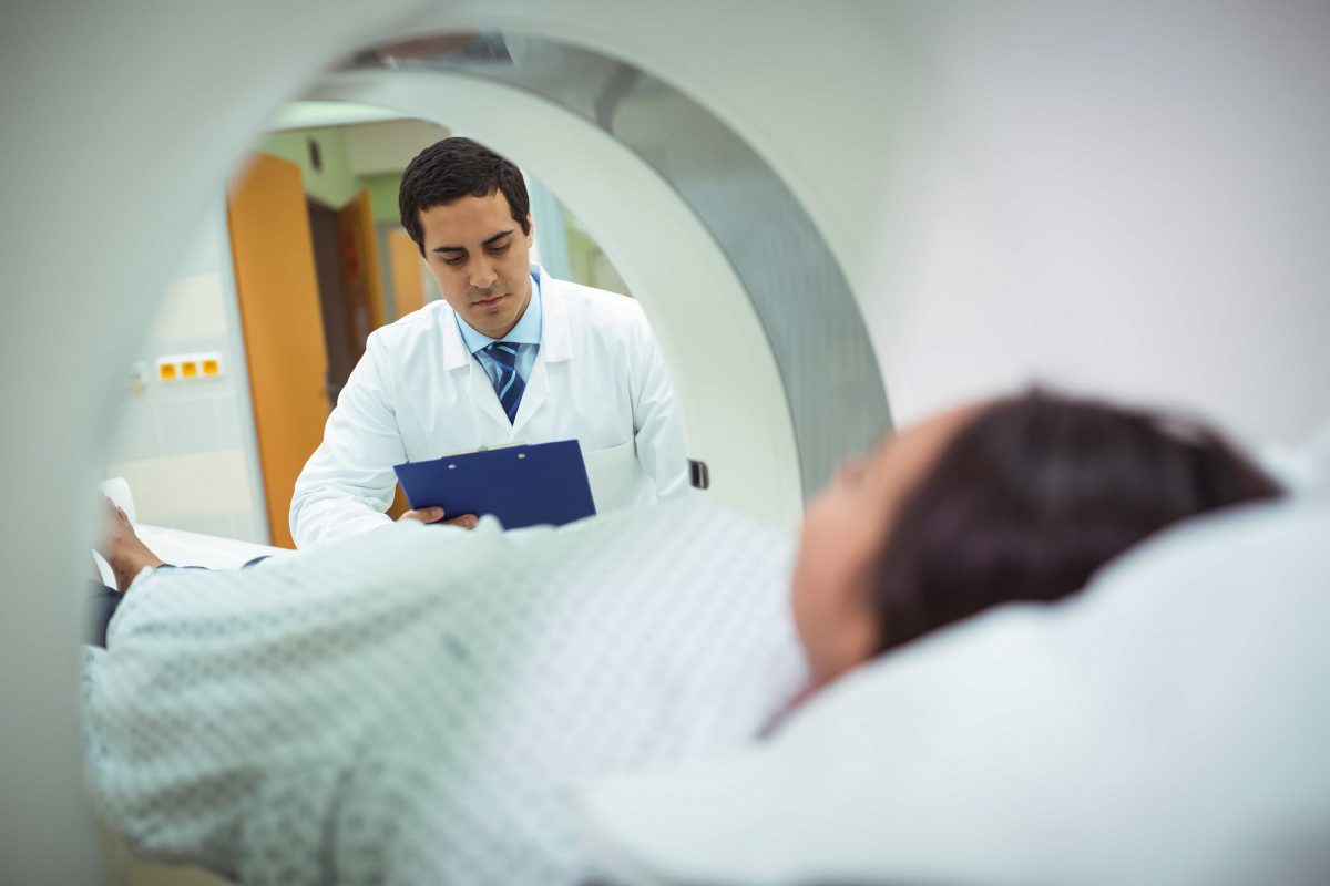 A doctor reviews his notes as the patient awaits an MRI