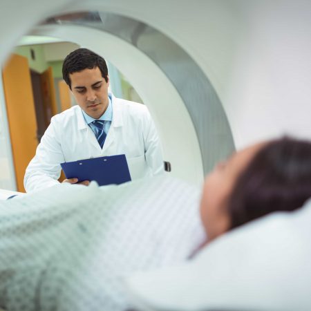 A doctor reviews his notes as the patient awaits an MRI