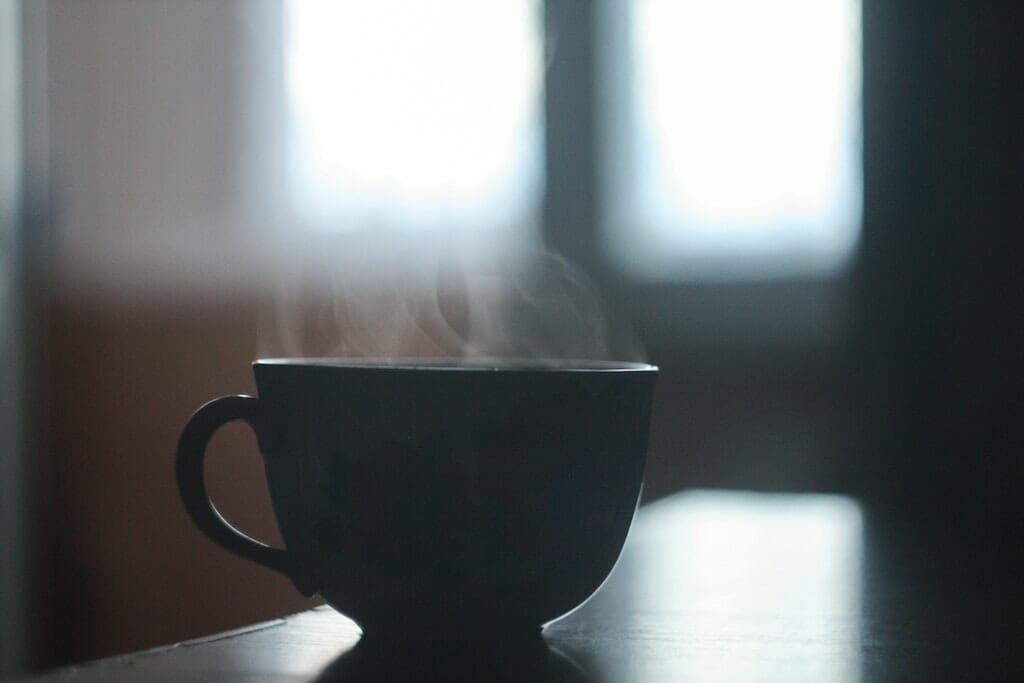 Steaming cup of coffee sitting on kitchen table.