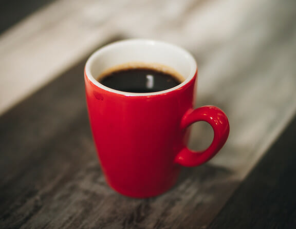 Red coffee cup on wooden table filled with coffee