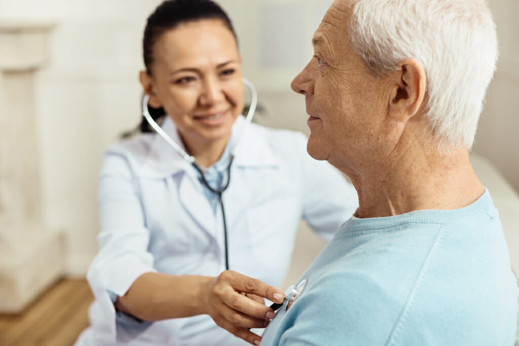 Clinician using stethoscope to hear lungs in patient's chest.