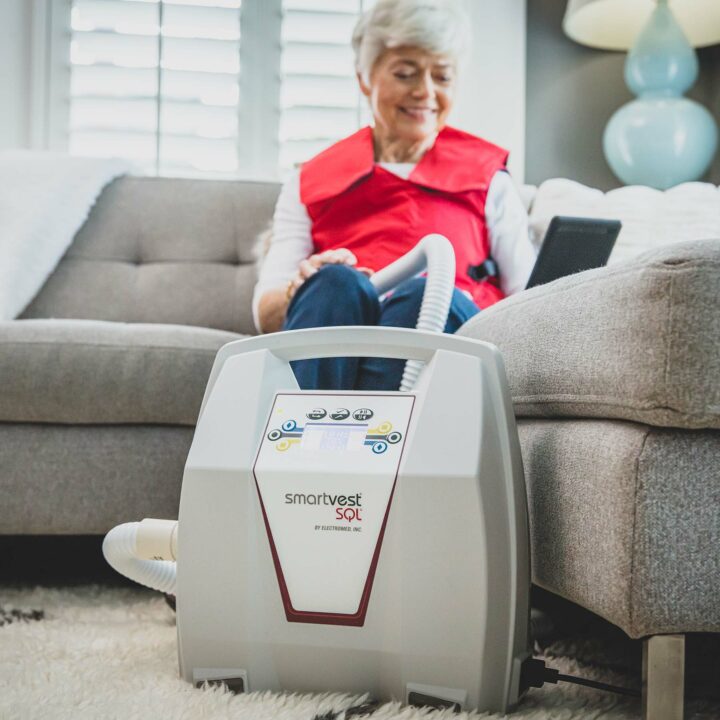 A woman sits behind her SmartVest generator during therapy