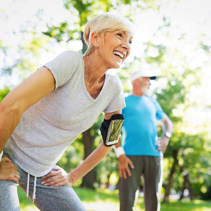 mature couple stretching outdoors in a lush park