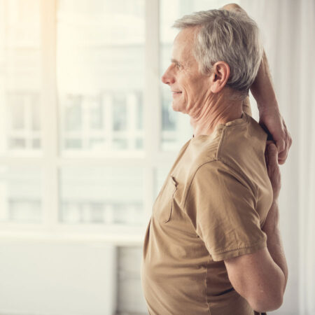 Older man stretching his arms and back for good posture.